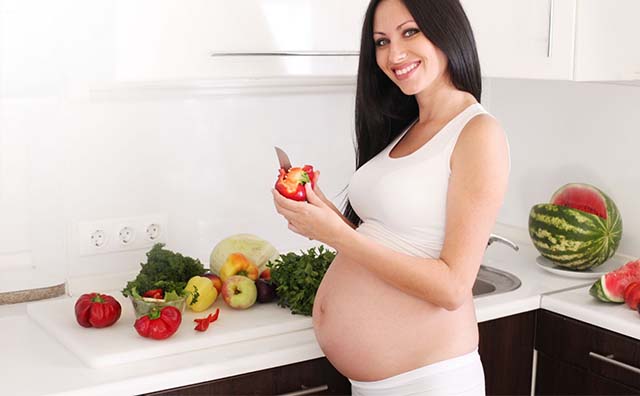 Беременная девушка режет овощи