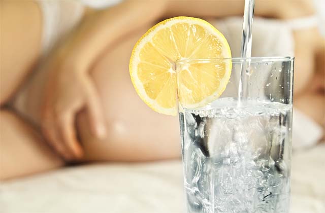 Вода с лимоном на фоне девушки